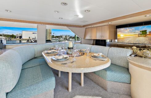 Yacht's kitchen booth with teal upholstered cushions and light tan quartz table