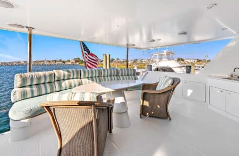 Yacht's aft deck with brown wicker chairs, white table, and seating area with light green cushions
