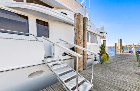 White yacht with metal dock steps docked at a harbor