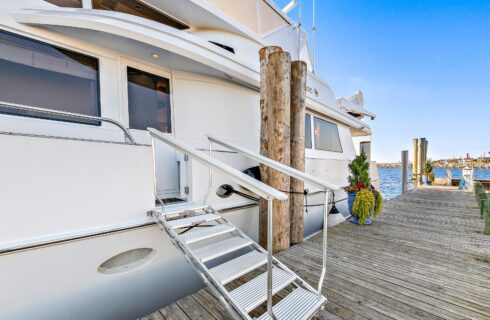 White yacht with metal dock steps docked at a harbor