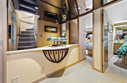 Yacht hallway between bedrooms with light colored walls and carpeting and large mirror