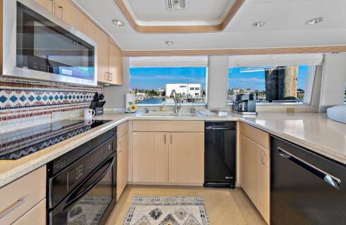 Kitchen on a yacht with light colored cabinets and countertops and black appliances