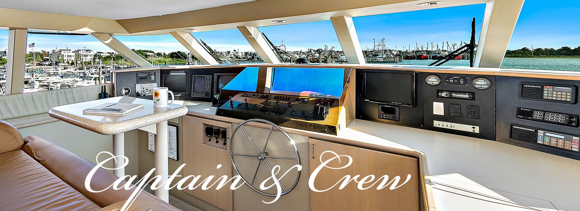 Bridge of yacht with light brown leather chair and small table and the words Captain & Crew in white