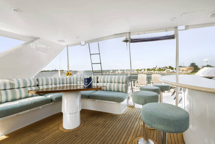 Yacht's bridge deck with white table and seating area with light green cushions