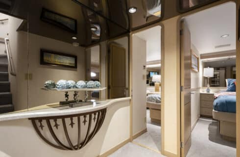 Yacht hallway between bedrooms with light colored walls and carpeting and large mirror