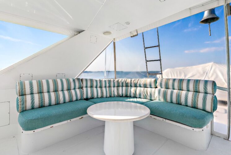 Yacht's bridge deck with white table and seating area with light green cushions