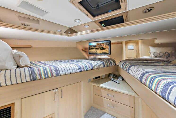 Yacht v-berth bedroom with colorful bedding, storage cabinets, and TV