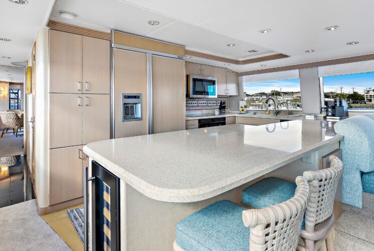 Kitchen on a yacht with light colored cabinets and countertops and black appliances