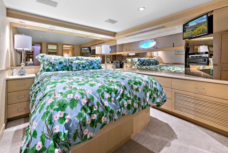 Yacht bedroom with colorful bedding, storage cabinets, and TV