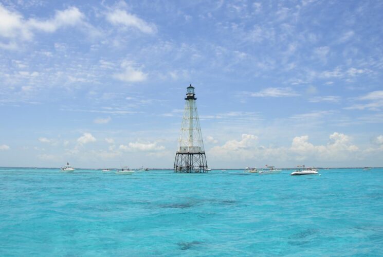 Metal lighthouse surrounded by bright blue water