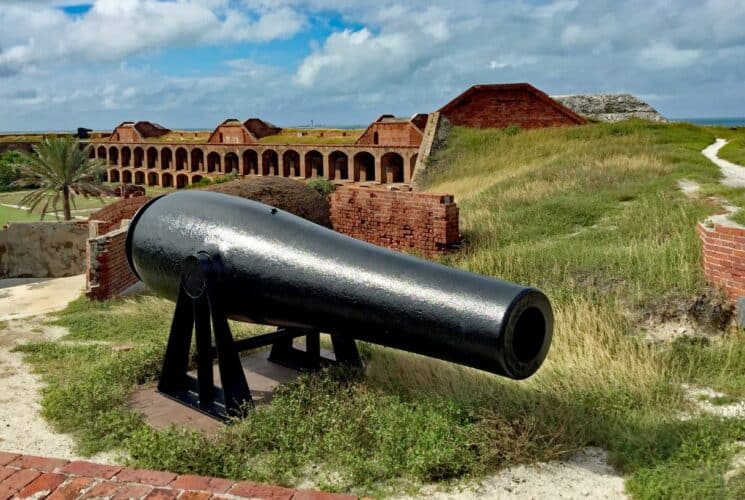 Antique black canon with old fort built into bunker near the ocean