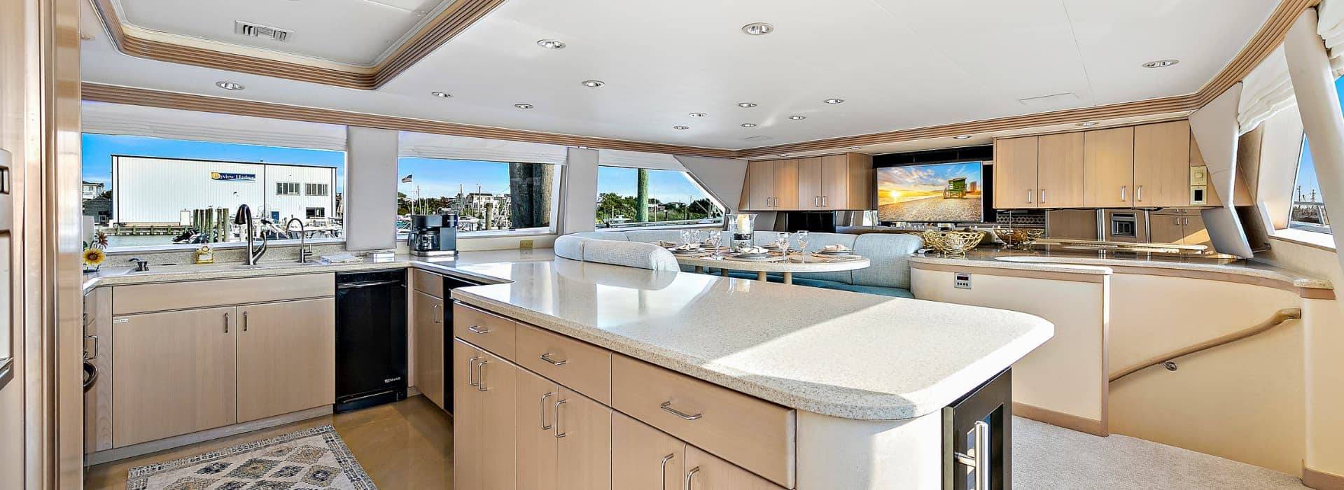 Kitchen on a yacht with light colored cabinets and countertops and black appliances